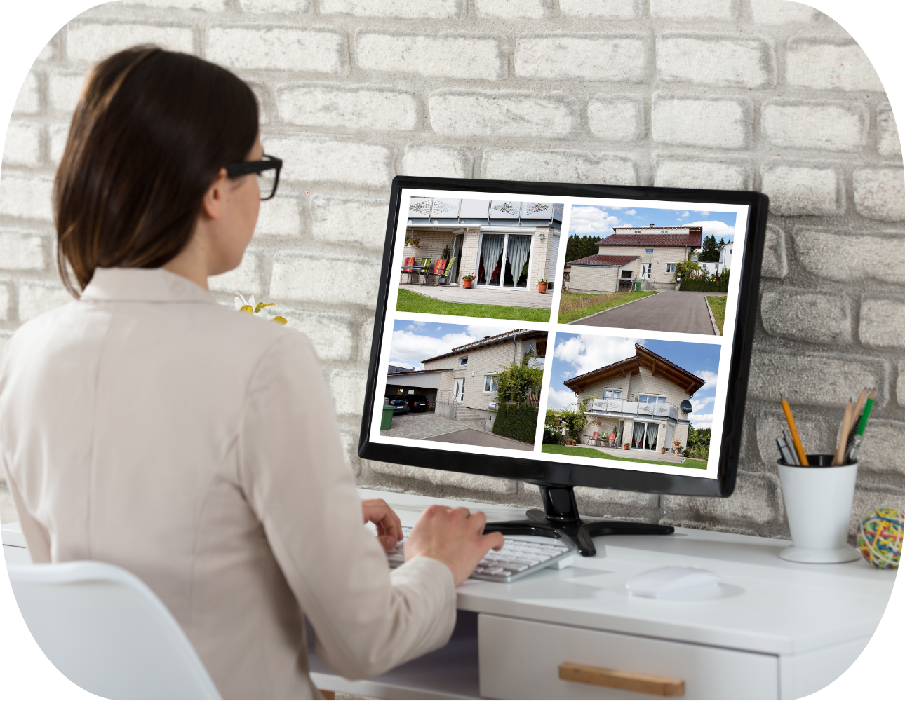 Real estate agent browsing property listings on a computer screen, reviewing multiple home options in a modern office.