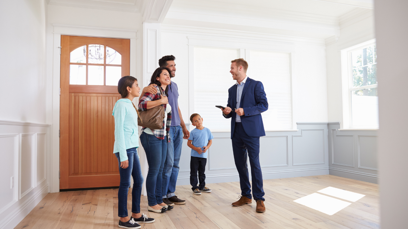 Real estate agent showing a modern home to a happy family, discussing property details in a bright and spacious living room.